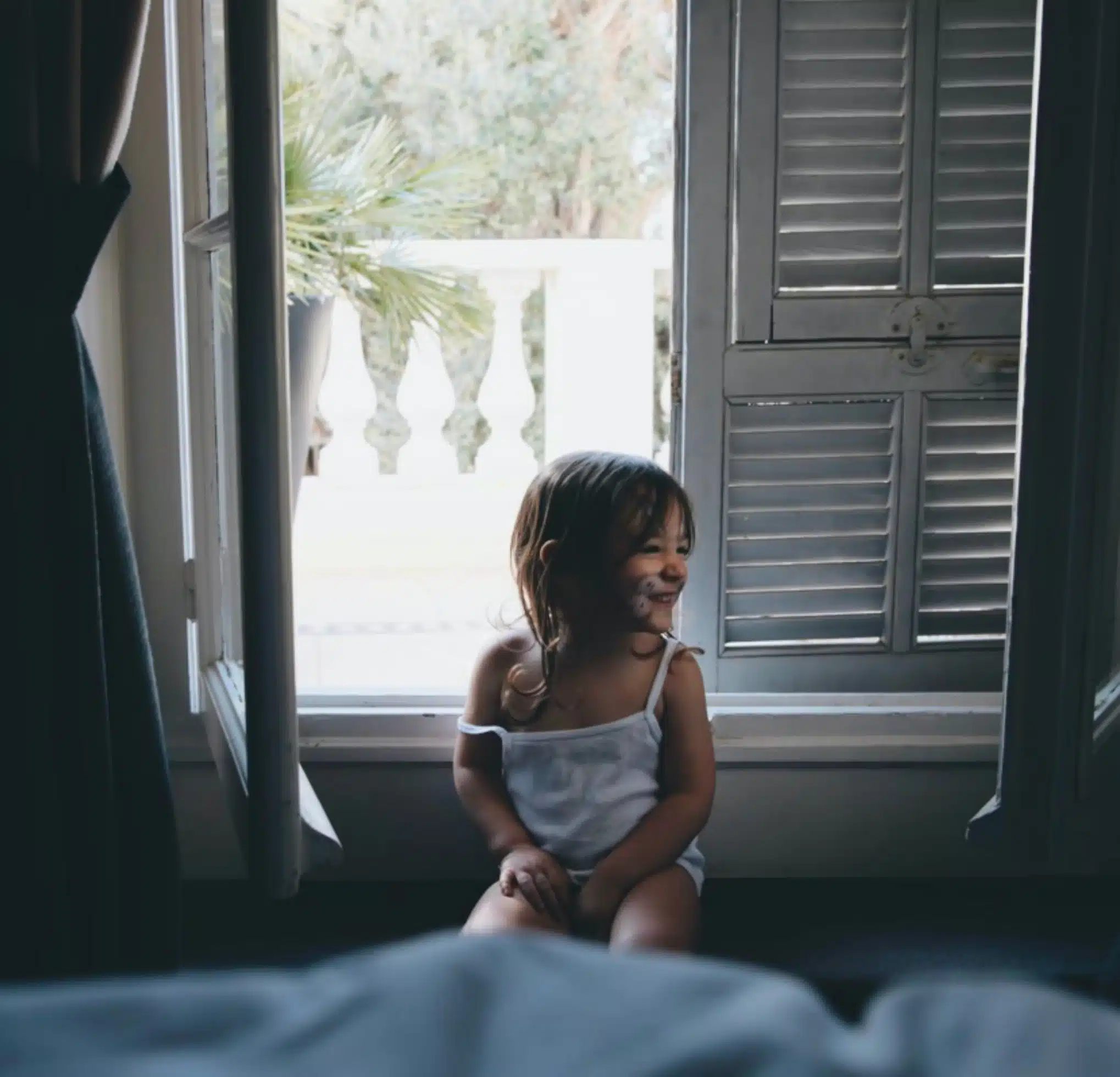 Delighted little girl in a hotel room, smiling with a mouthful of rich chocolate cake, capturing a moment of indulgent pleasure