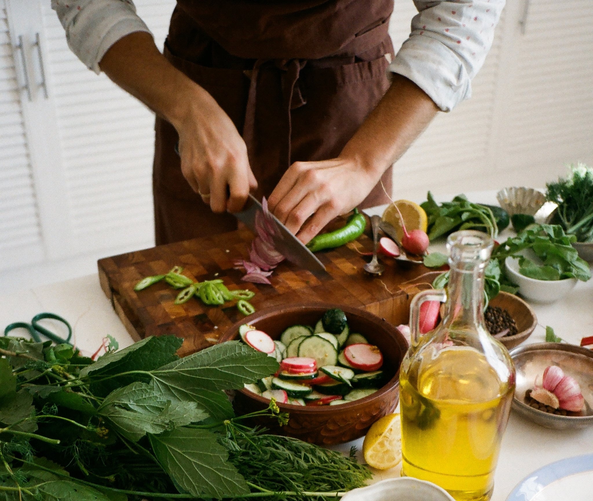 Skilled personal chef preparing a healthy meal with fresh greens and slicing an onion, showcasing Grapevine Placements Agency's extensive range of domestic help services, and culinary expertise