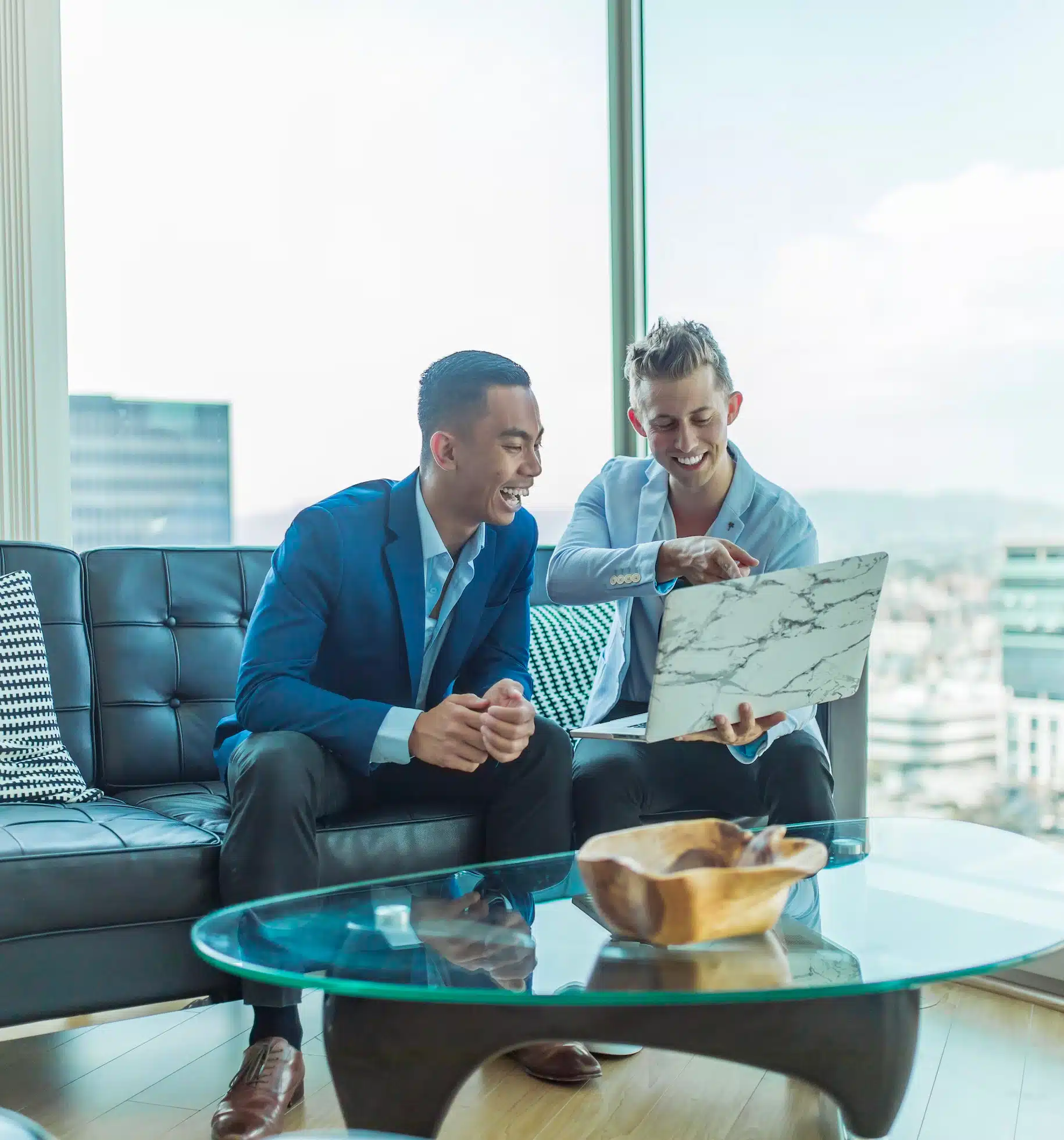 Two focused men in an office setting, enthusiastically achieving a breakthrough on their laptop, embodying teamwork and innovation