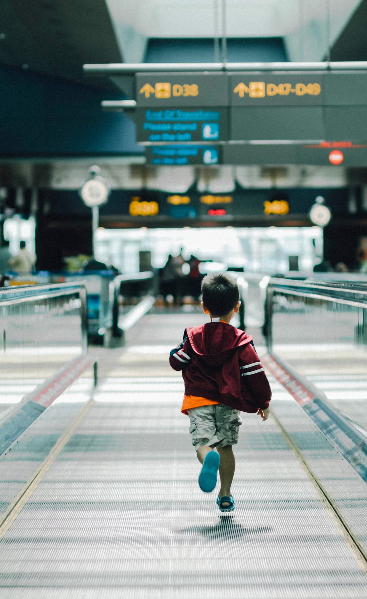 A young boy energetically running through the airport terminal, capturing a moment of excitement or haste.