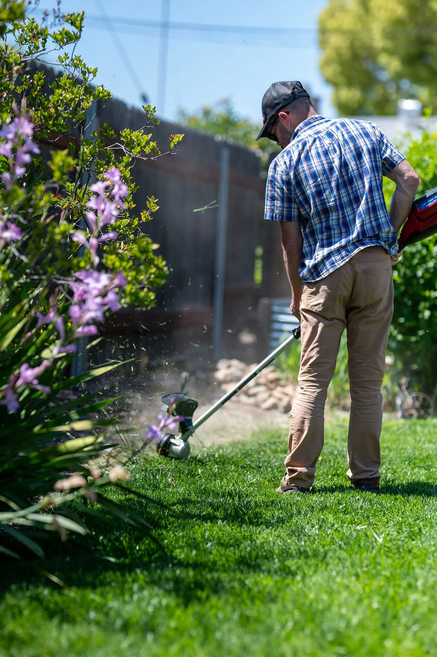 A diligent gardener meticulously trimming the grass, ensuring a neat and well-kept lawn with his lawn mower