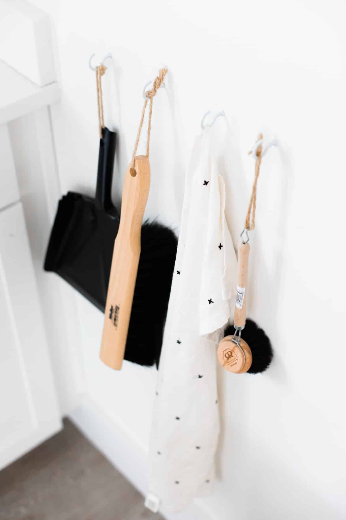 Minimalist housekeeping tools hung neatly on a white wall.